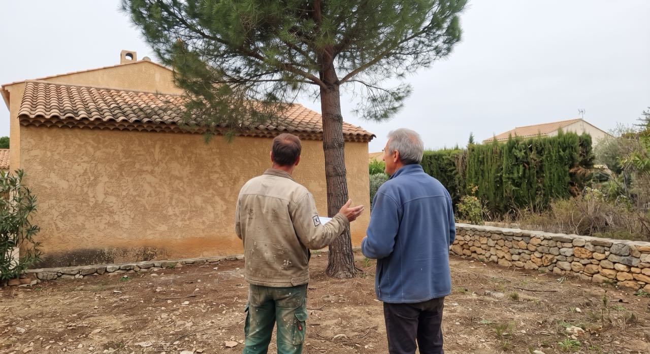 L'artisan explique l'intervention au client sous l'arbre